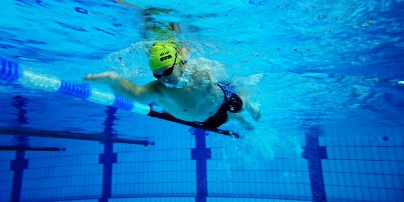 Undervannsbilde av en som svømmer i bassenget. Foto.